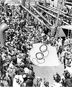 الفريق، الظاهر في الصورة يستعد لرفع علم الأولمبياد فوق السفينة<i> مانهاتن</i>. قاد أفري بروندج، رئيس اللجنة الأولمبية الأمريكية الوفد.