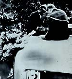 أوينز، ابن مزارعي ألاباما، وهو محاط برجال الأمن خلال فترة إقامته في ألمانيا. يقوم غالبية الجمهور الألماني بتحيته بصوت عالٍ في كل مرة يدخل فيها أرض الاستاد. 31 يوليو، 1936.