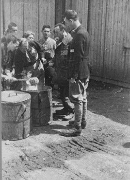 Prisoner forced laborers crowd around containers of food. Plaszow labor camp, Poland, 1943-1944.