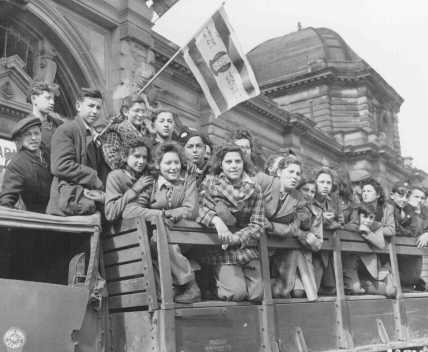 Jewish refugee children gather in the U.S. zone of occupation in Germany, en route to Palestine. One refugee waves a Zionist flag. Frankfurt, Germany, April 10, 1946.