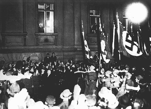 D’une fenêtre de la chancellerie du Reich, le président allemand Paul von Hindenburg regarde un défilé nazi aux flambeaux en l’honneur de la nomination d’Hitler au poste de chancelier allemand. Berlin, Allemagne, 30 janvier 1933.