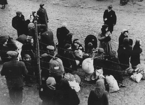 Jewish families with bundles of belongings during deportation from the Kovno ghetto to Riga in neighboring Latvia. Kovno, Lithuania, 1942.