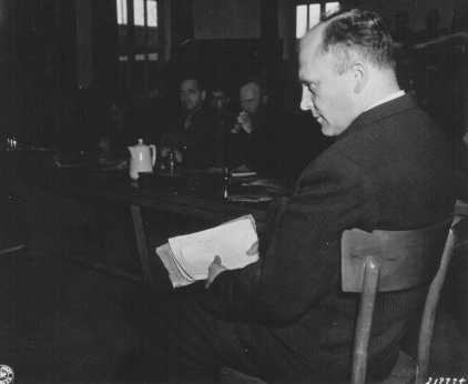 Friedrich Hoffman, segurando uma pilha de registros de morte, testemunha sobre o assassinato de 324 padres católicos que foram expostos à malária durante experiências médicas no campo de concentração de Dachau. Dachau, Alemanha, 22 de novembro de 1945.
