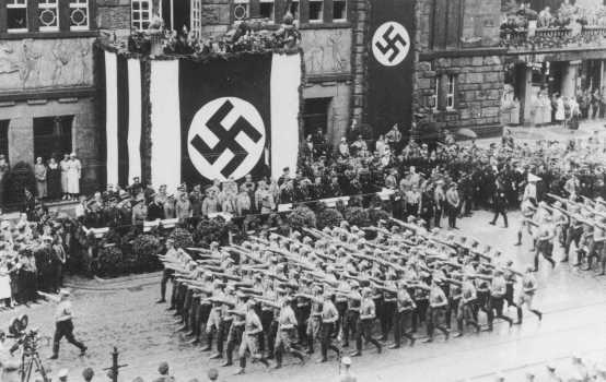 Bataillons de combattants de rue nazis saluant Hitler au cours d’un défilé des SA (Sturmabteilung, section d’assaut) dans les rues de Dortmund. Allemagne, 1933.