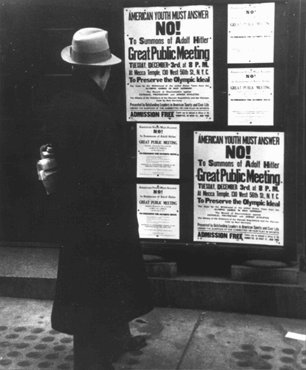 A pedestrian pauses to read a notice announcing an upcoming public meeting, scheduled for Tuesday, December 3, to urge Americans to boycott the 1936 Berlin Olympics. New York, United States, 1935.