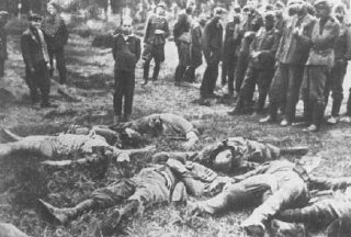 اعضای جوخه سیار اعدام پیش از تیرباران یک جوان یهودی. اعضای کشته شده خانواده این جوان در برابر او روی زمین افتاده اند. افراد سمت چپ تصویر، آلمانی های محلی هستند که به جوخه کمک می کردند. اسلاروف، اتحاد جماهیر شوروی، 4 ژوئیه 1941.