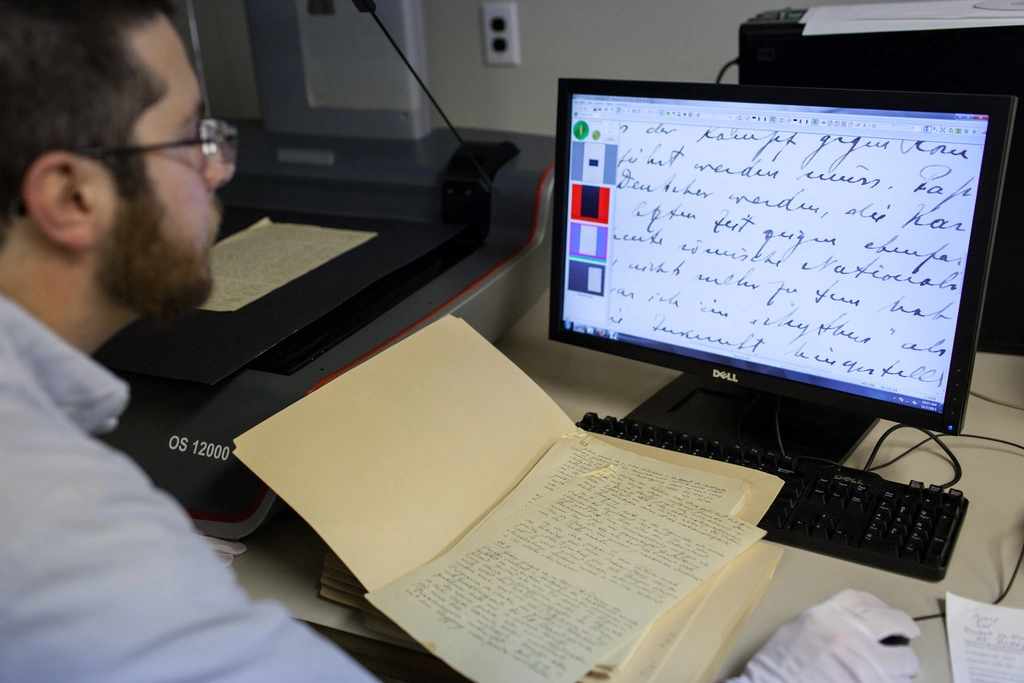 A curator scanning pages of a book into a computer