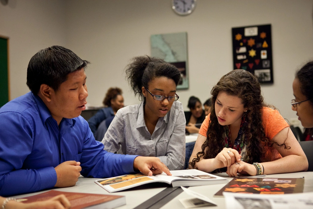 Three students examine documents in a classroom at the Museum