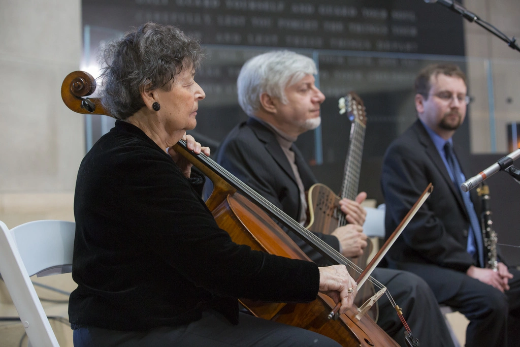 A survivor volunteer plays music at a Museum remembrance event.