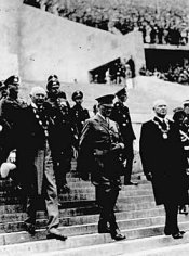 هتلر يدخل الاستاد مع منظم الأولمبياد الألماني تيودر ليوالد ورئيس اللجنة الأولمبية الدولية الكونت هنري بيليت-لاتور. 1 أغسطس، 1936.