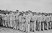 Prisoners during a roll call at the Buchenwald concentration camp. Their uniforms bear classifying triangular badges and identification numbers. Buchenwald, Germany, 1938-1941.