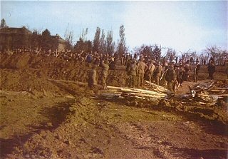 American soldiers watch as German civilians bury the...
