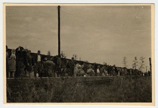 Displaced persons stand on a train platform in the...