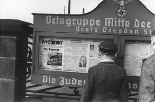 ドレスデン地域のナチス政党本部の入口近くの掲示板に貼られた「シュテルマー」紙を読むドイツ人少年。