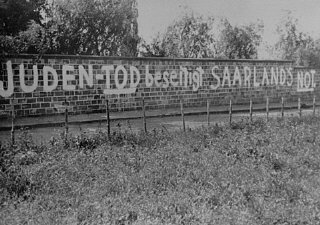 ユダヤ人墓地の塀に「ユダヤ人の死によってザールラントの困窮が終わる」と書いた反ユダヤ主義の落書き。 ベ...