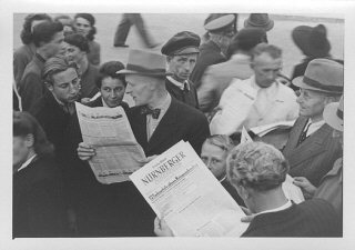 国際軍事裁判の判決を報道する「ニュルンベルカー」紙の号外を街角で読む人々。