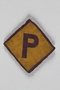 Used forced labor badge, yellow with a purple P, sewn to gray felt backing for use by a Polish forced laborer