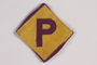 Forced labor badge, yellow with a purple P, worn by a Catholic Polish soldier interned by the Germans