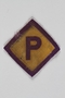 Forced labor badge, yellow with a purple P, to identify a Polish forced laborer acquired by a US soldier