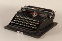 2000.281.1_a front
Continental typewriter with a swastika and SS emblem key and a removable lid

Click to enlarge