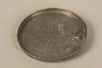 2005.448.1 front
Metal lid from a cremation urn stamped Dachau

Click to enlarge