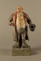 Painted pottery figure of a stereotypical Jewish merchant holding gold coins