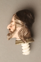 2016.184.614 left side
Porcelain bottle stopper with a painted finial depicting a Jewish stereotype

Click to enlarge